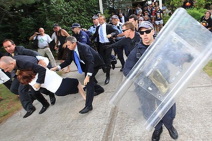 La primera ministra Julia Gillard �s arrossegada a un cotxe pel seu equip de seguretat enmig d'enfrontaments entre la policia i manifestants. Foto: Alex Ellinghausen